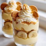 Close-up of two Banana Pudding Parfait Cups layered with vanilla pudding, fresh bananas, vanilla wafers, and whipped cream.