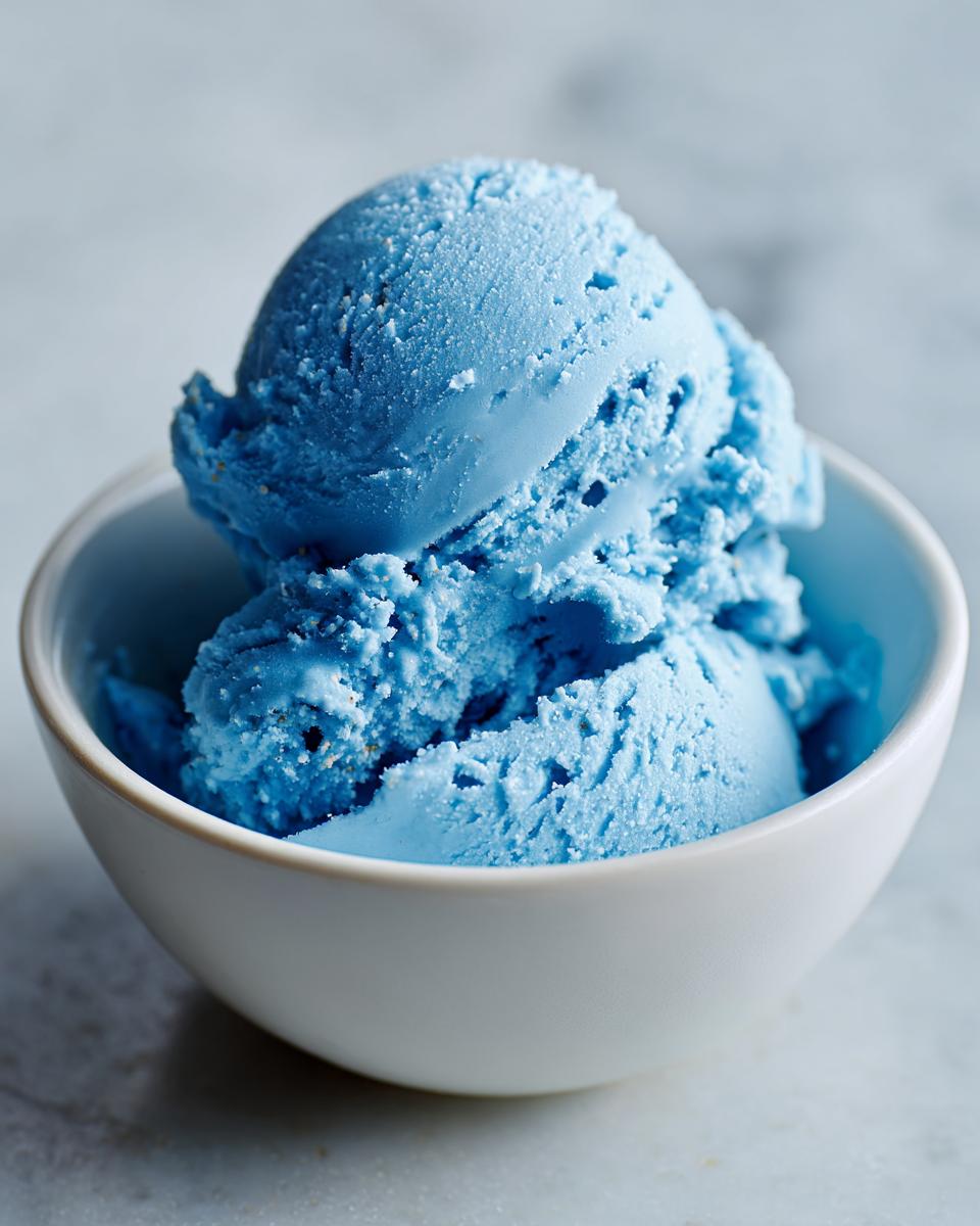 Delicious Blue Moon Ice Cream Recipe 4 Close-up of a white bowl filled with vibrant blue scoops of Blue Moon Ice Cream.