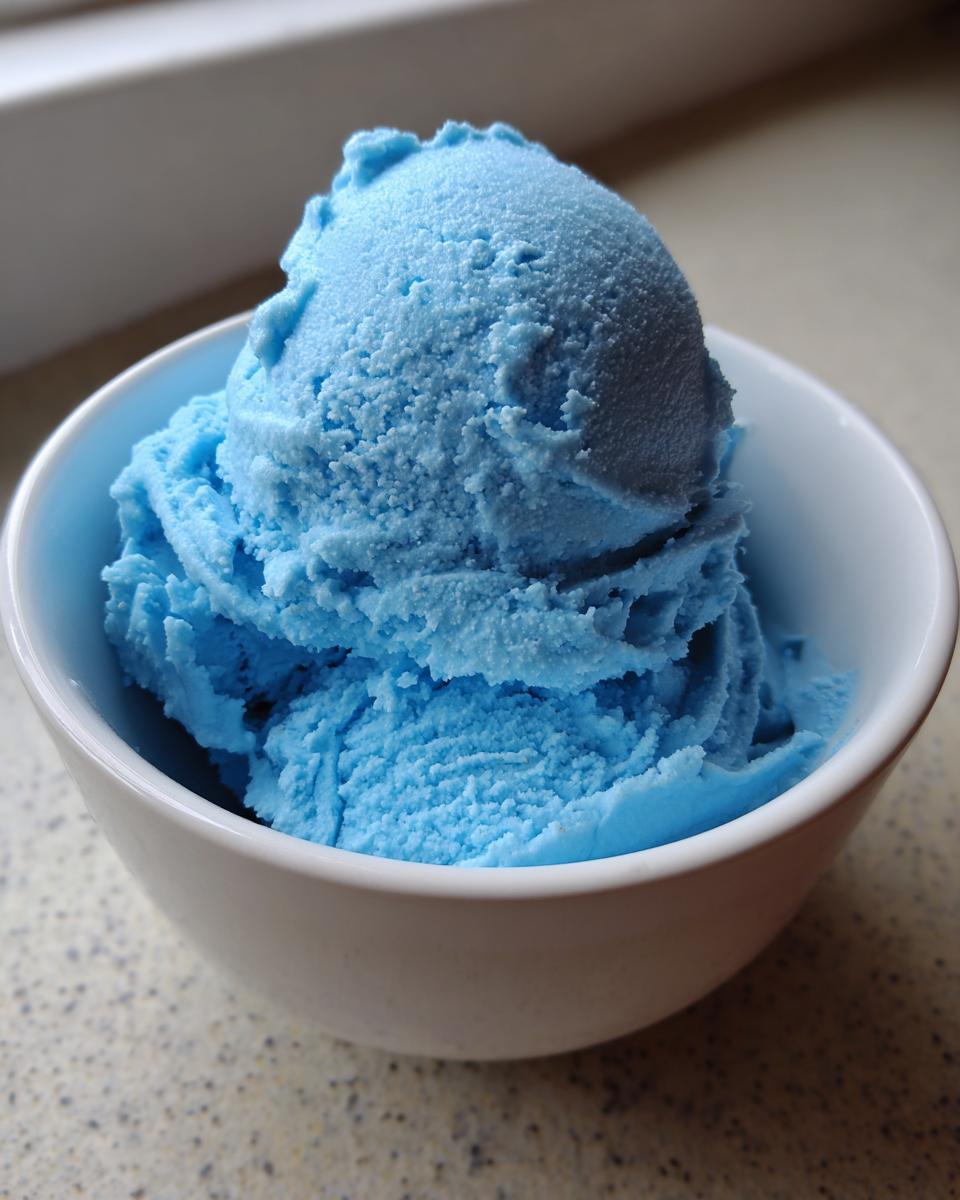 A white bowl filled with scoops of bright blue Blue Moon ice cream.