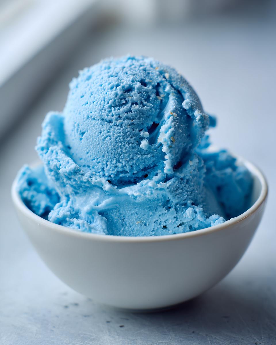 Delicious Blue Moon Ice Cream Recipe 5 A close-up of a white bowl filled with scoops of bright blue Blue Moon Ice Cream.