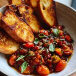 A bowl of Bruschetta Dip with Garlic Crostini, featuring fresh tomatoes, herbs, and toasted bread slices.
