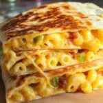 Close-up of a Cheesy Mac and Cheese Quesadilla cut in half, revealing gooey mac and cheese and green peppers.