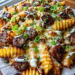 Close-up of Cheesy Ranch Loaded Fries with Sausage, topped with melted cheese, sausage slices, and green onions.