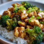 A delicious bowl of Chicken and Broccoli Stir Fry served over fluffy white rice, garnished with green onions.