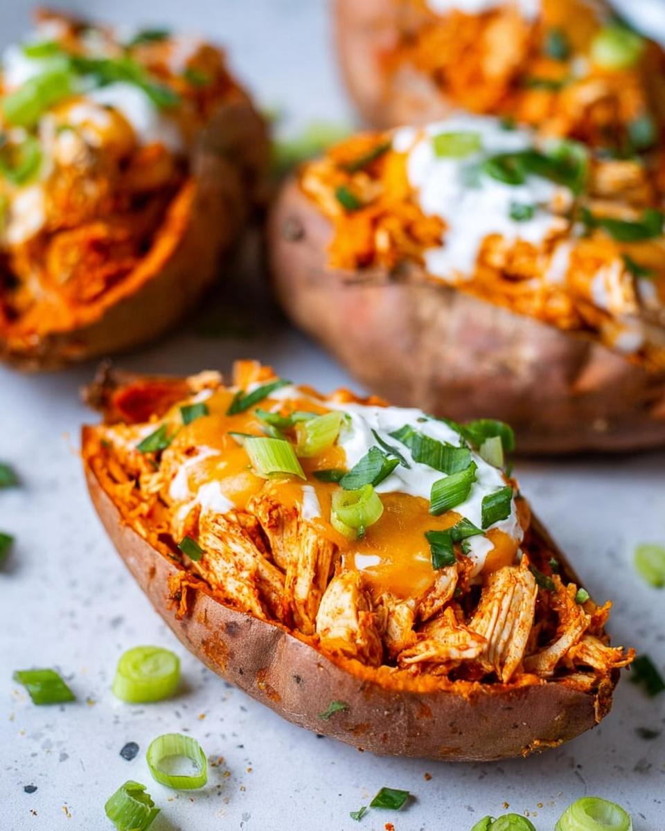 Easy Chicken Enchilada Sweet Potatoes 4 Close-up of a Chicken Enchilada Stuffed Sweet Potato topped with sour cream, cheese sauce, and green onions.
