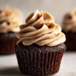 A close-up of a decadent chocolate cupcake topped with swirls of creamy peanut butter buttercream frosting.