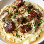 Close-up of Creamy Garlic Butter Steak Bites served over mashed potatoes, garnished with parsley.