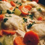 Close-up of delicious Crockpot Chicken and Dumplings with tender chicken, carrots, and fluffy dumplings in a creamy broth.