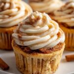 Close-up of a Delicious Cinnamon Roll Cupcake topped with swirled cream cheese frosting and a dusting of cinnamon.