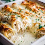 Close-up of cheesy Chicken Enchiladas with Sour Cream White Sauce, garnished with parsley.