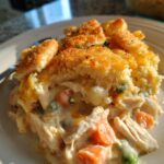 A close-up of a serving of Easy Ina Garten Inspired Chicken Casserole, featuring shredded chicken, carrots, peas, and a creamy sauce topped with golden breadcrumbs.