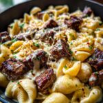 Close-up of a bowl of Garlic Butter Steak Shell Pasta Skillet, featuring tender steak pieces and shell pasta in a creamy sauce, topped with cheese and parsley.