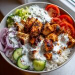 A delicious Greek Chicken Gyro Rice Bowl with grilled chicken, rice, cucumber, tomato, red onion, and tzatziki sauce.