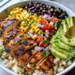A vibrant Grilled Avocado Chicken Bowl with Corn Salsa, featuring sliced grilled chicken, avocado, corn, black beans, and rice.