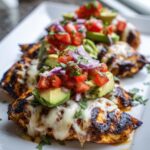 Close-up of grilled California Avocado Chicken topped with melted cheese, diced tomatoes, avocado, and red onion.