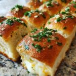 Close-up of Hawaiian Roll Mini Grilled Cheese, showing gooey melted cheese oozing out, topped with garlic and parsley.