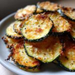 A close-up of a pile of crispy Keto Air Fryer Zucchini Chips seasoned with cheese and herbs.