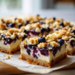 Close-up of Lemon Blueberry Cheesecake Cookie Bars, showcasing a creamy cheesecake layer with fresh blueberries and a crumbly topping.