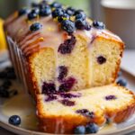 A slice of moist Lemon Blueberry Pound Cake topped with glaze and fresh blueberries.
