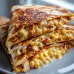 Close-up of a Mac and Cheese Chicken Quesadilla cut into triangles, showing gooey cheese, pasta, and chicken.