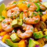 A vibrant bowl of Mango Pineapple Shrimp Salad with Avocado, featuring plump shrimp, diced mango, avocado, and red onion.