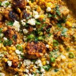 Close-up of Mexican Street Corn Chicken Skillet Dinner with seasoned chicken pieces, corn, crumbled cheese, and cilantro.