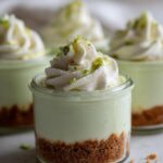 Close-up of an easy no bake key lime cheesecake jar topped with whipped cream and lime zest.