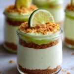 Close-up of a No Bake Key Lime Cheesecake Parfait in a jar, topped with graham cracker crumbs and a lime slice.