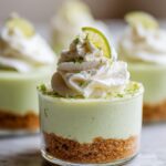 Close-up of an easy no bake lime cheesecake cup dessert with whipped cream and a lime slice.