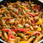 A close-up of a rich and creamy One Pot Cajun Chicken Pasta with bell peppers and parsley.