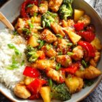 A close-up of a Pineapple Teriyaki Chicken Bowls recipe, featuring chicken, pineapple chunks, red bell peppers, and broccoli over white rice.
