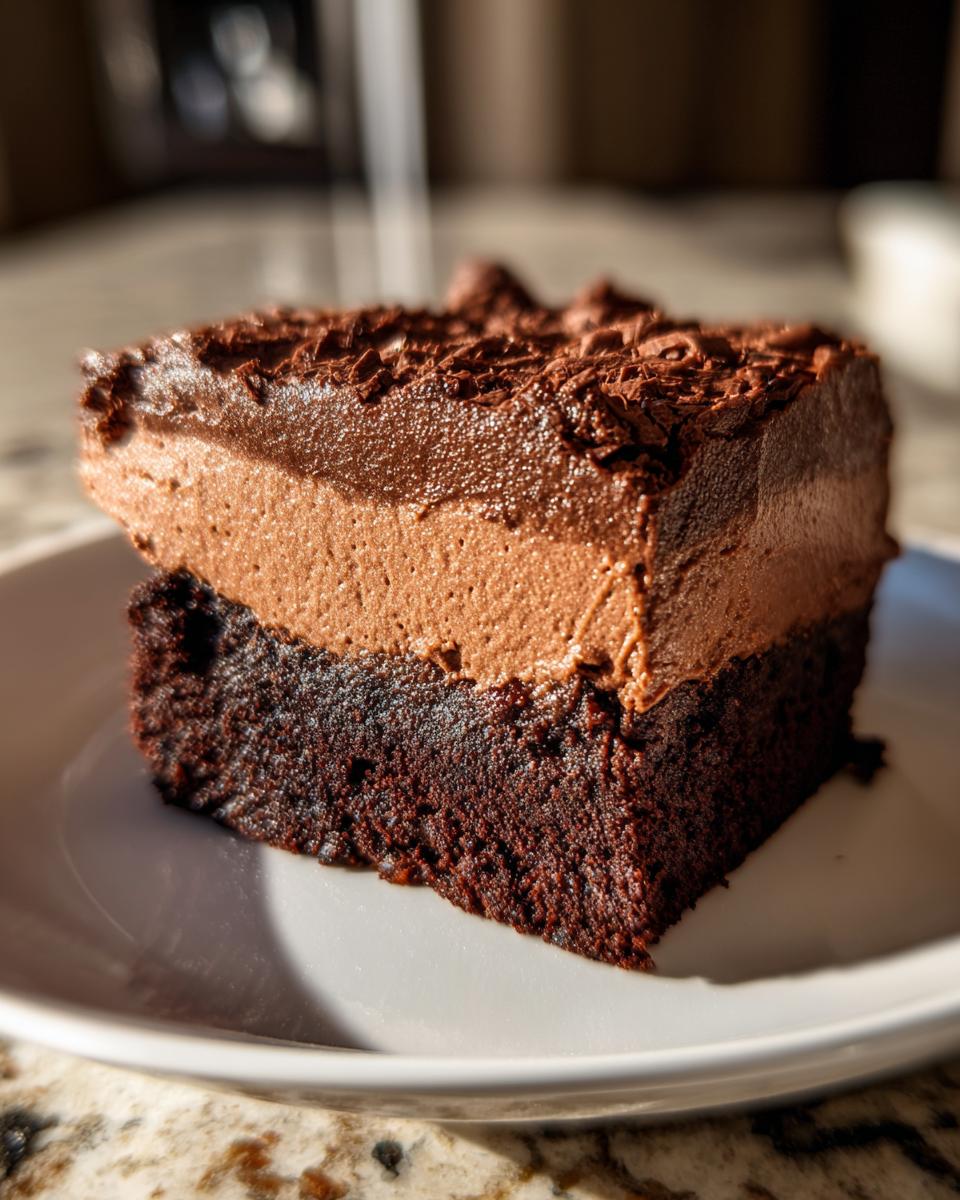 Irresistible Rich Chocolate Mousse Brownies 5 A decadent slice of Rich Chocolate Mousse Brownies, featuring a dense brownie base topped with smooth chocolate mousse and chocolate shavings.