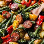 Close-up of a colorful sheet pan sausage and veggies recipe, featuring sliced sausage, broccoli, green beans, potatoes, and bell peppers.