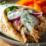 A delicious Slow Cooker Chicken Gyro filled with shredded chicken, creamy tzatziki, red onion, and herbs.
