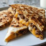 Close-up of delicious Smashburger Quesadillas with crispy beef and gooey melted cheese, cut into wedges.