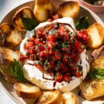 A close-up of Whipped Ricotta Bruschetta with fresh tomato basil topping and toasted bread slices.