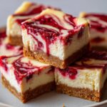 A stack of delicious White Chocolate Raspberry Cheesecake Bars with a graham cracker crust and raspberry swirl.